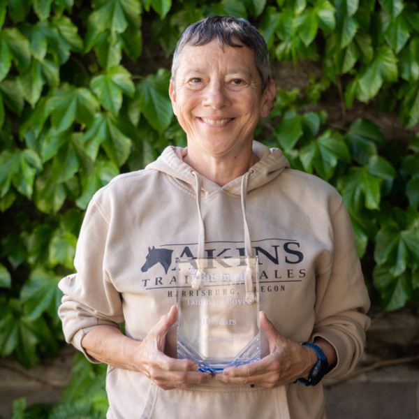 Employee recognized for 10 years of faithful service while holding a commemorative award outdoors on campus