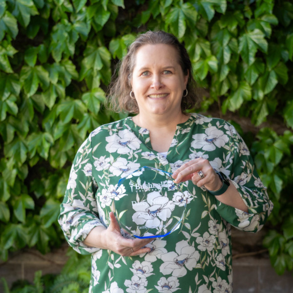 Employee recognized for 20 years of faithful service while holding a commemorative award outdoors on campus