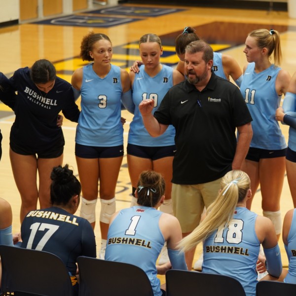 Bushnell University women’s volleyball team gathered around their coach during competition